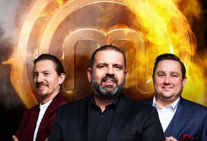 Three men in suits pose in front of a large glowing gold logo with flames in the background.