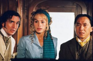 Three travelers in vintage clothing stand close together inside a wooden train carriage, looking surprised or alarmed at something off-camera.