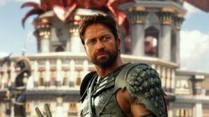 Rugged warrior in metallic, scale-like armor gazes off to the side with a fantasy city backdrop behind him.