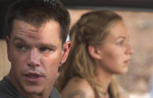 Close-up of a sweaty man looking to the left, with a blurred woman in the background.