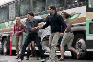 Group of young adults sprinting away from a green-and-brown bus on a city street, looking frightened. A crowd of people escapes a bus, zipping past it as they run in a line.