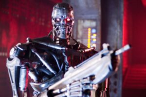 Close-up of a silver humanoid robot with glowing red eyes in a dark red-lit sci-fi environment