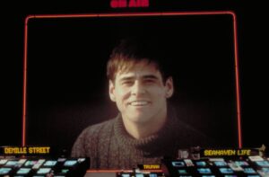 Large portrait of a smiling man on a dark screen framed by a red neon border; 'ON AIR' at the top and show labels below.